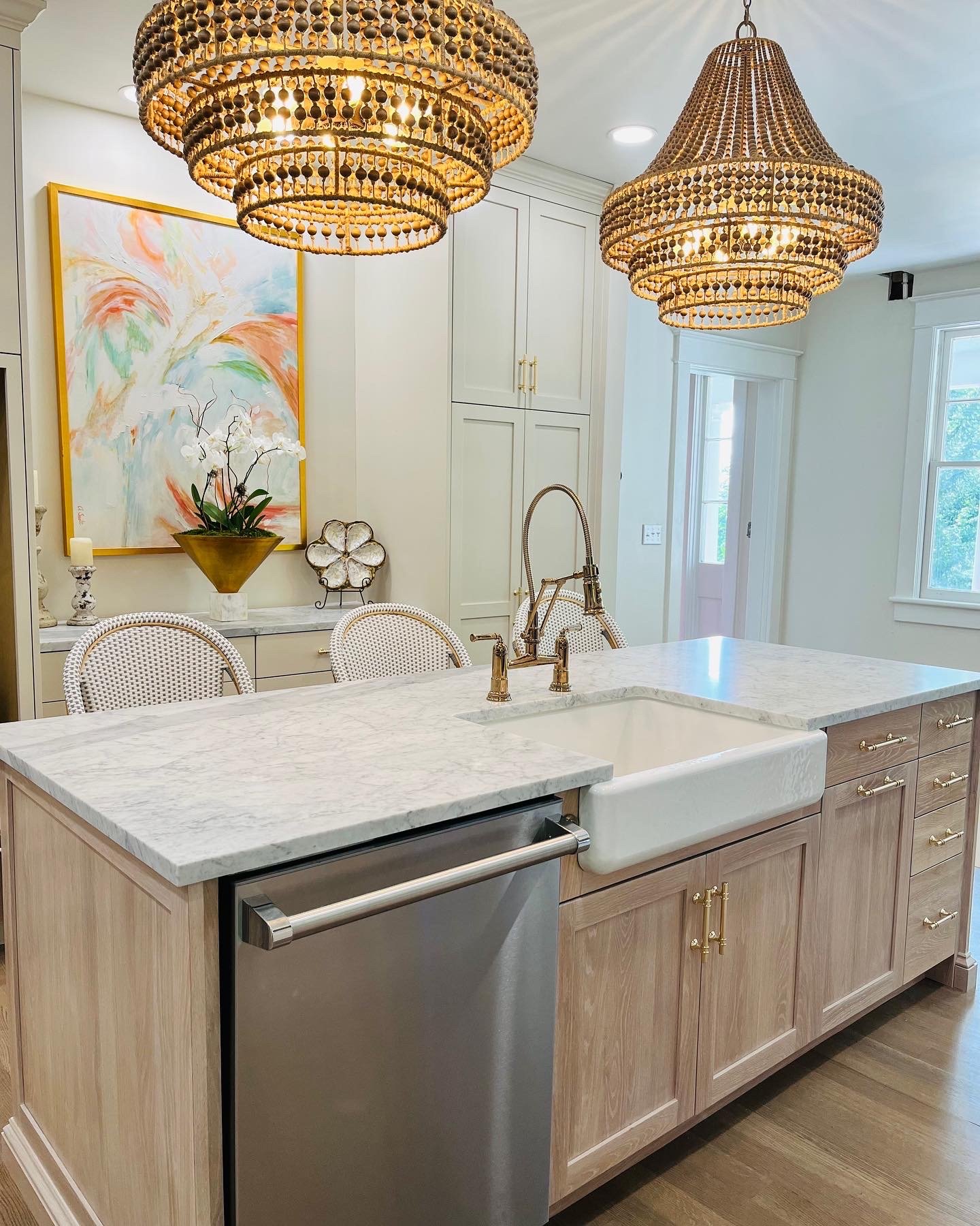 Kitchen with a light wood island, marble countertop, farmhouse sink and wood-bead pendant lights
